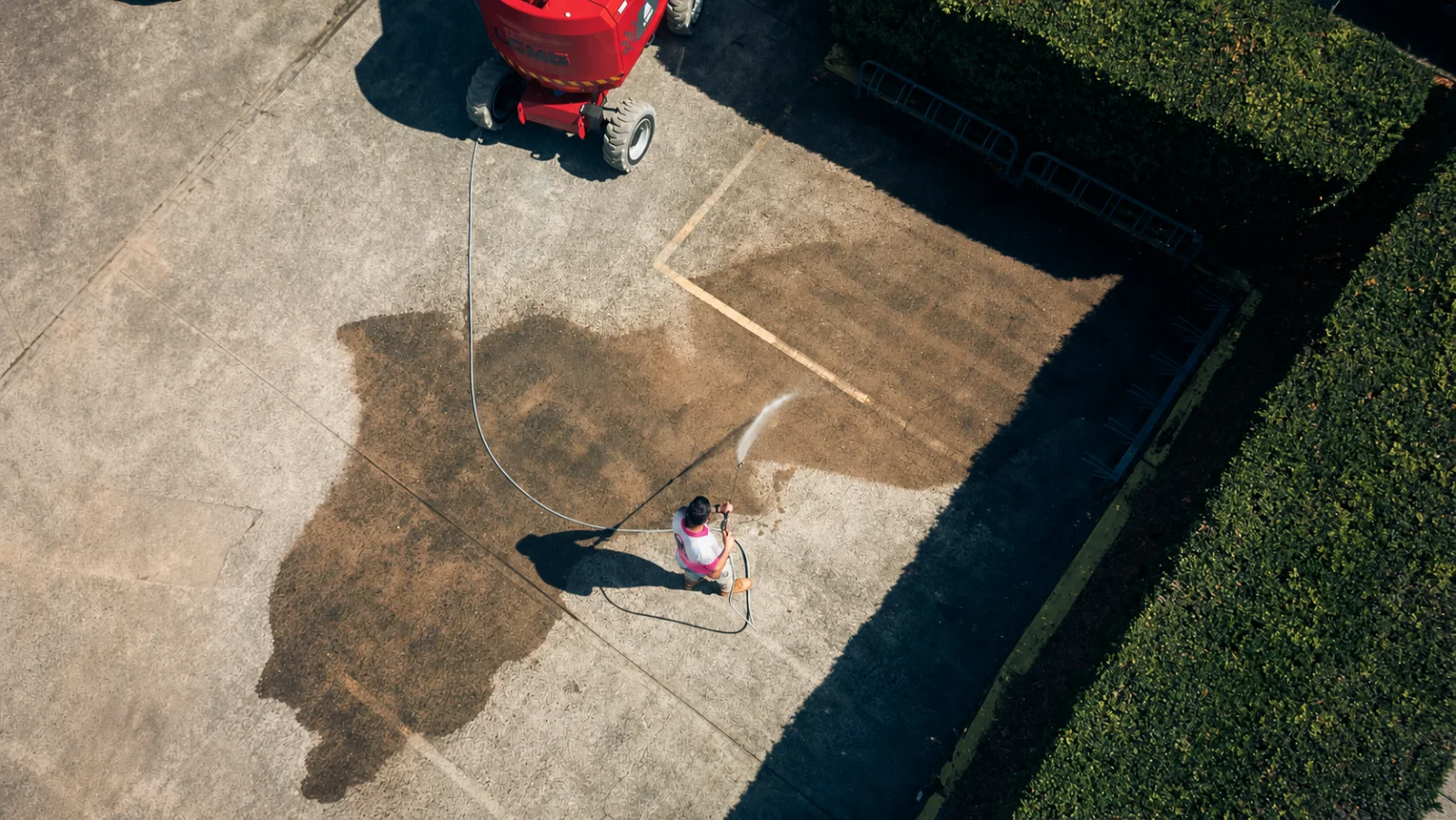 Overhead view of pressure washing a concrete driveway