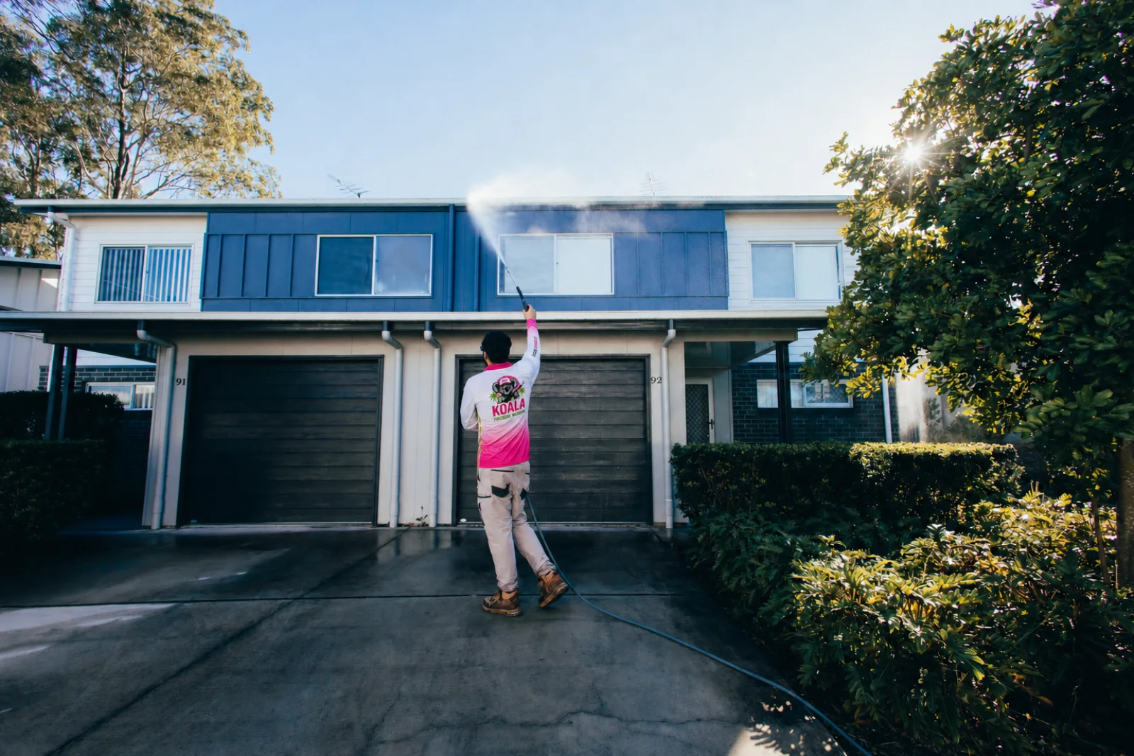Koala technician pressure washing a townhouse exterior